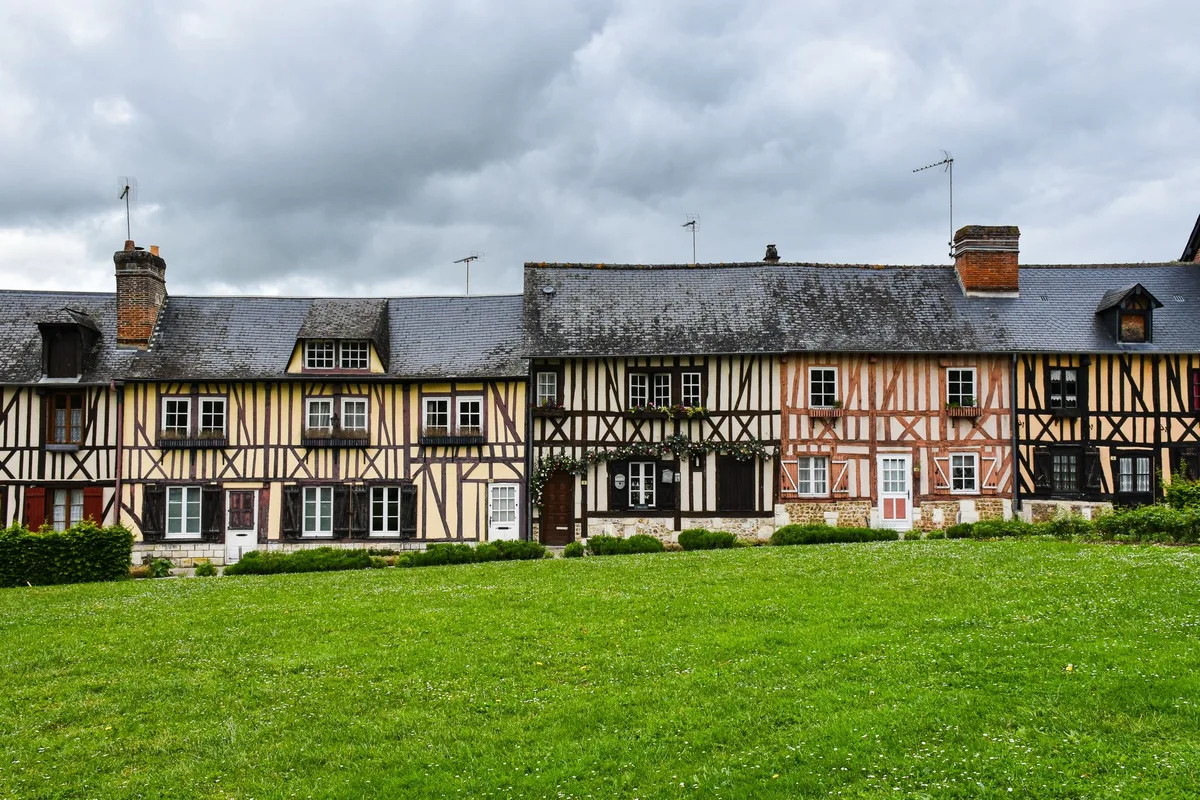 Rangée de maisons à colombages au bord d'une pelouse dans un village normand