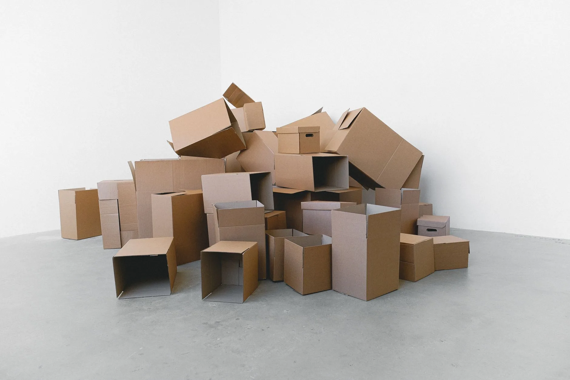 Pile de cartons de déménagement dans un grand local vide aux murs blancs
